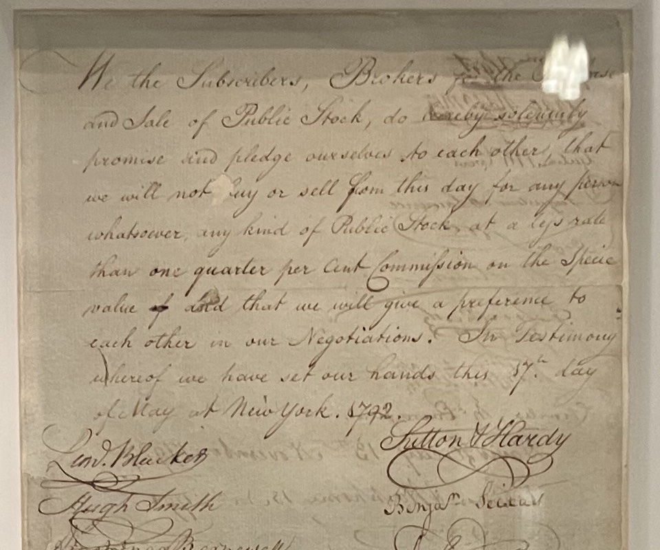 Detail of the agreement's handwriting. The legible lines read: we will not buy or sell from this day for any person whatsoever, any kind of Public Stock, at a less rate than one quarter per Cent Commission on the Specie value, and that we will give a preference to each other in our Negotiations. The first signatures begin below.